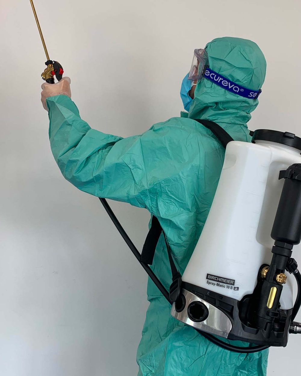 Technicien TOTEM 3D en combinaison de protection intégrale, pulvérisateur dorsal en main, pendant une désinfection